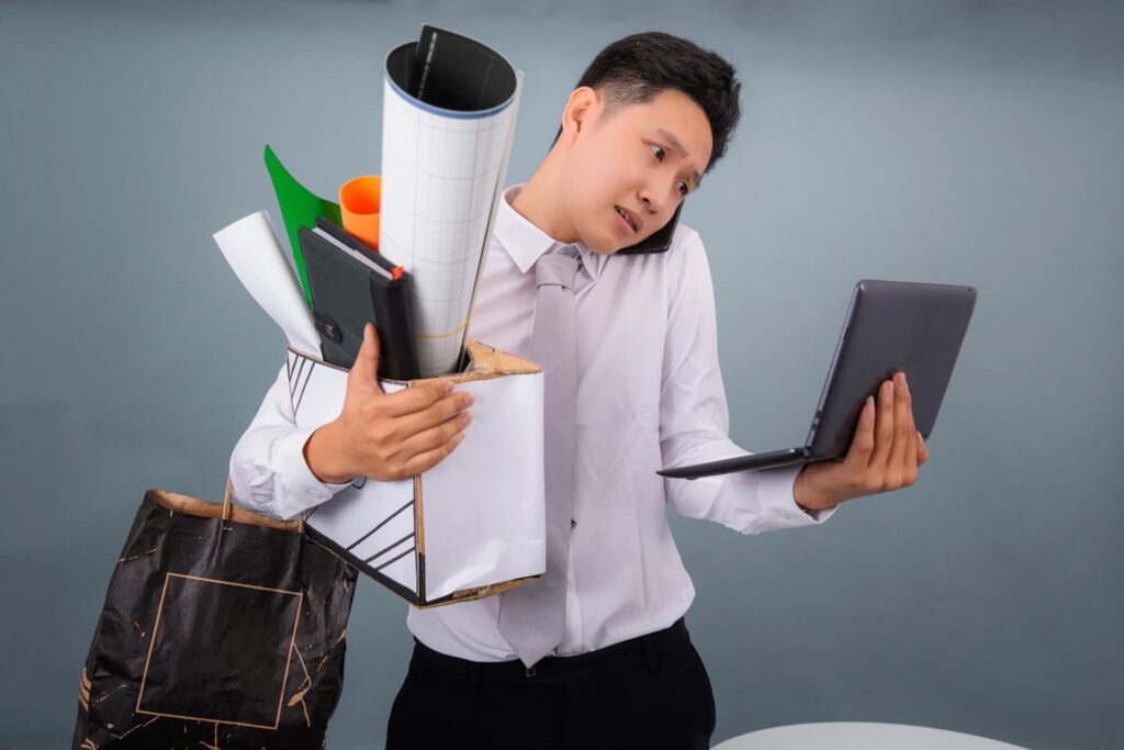 荷物やPCを両手いっぱいに持ち、大変そうなスーツ姿の外国人男性